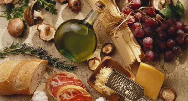 Arial view of a food board, Smörgåsbord, olive oil, dried meats, cheese, bread, mushrooms, grapes, rosemary and herds.